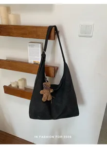Sac bandoulière noir tressé, sangle réglable et pendentif ourson brun, suspendu en intérieur
