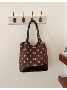 Bruine tas met suède-look, crèmekleurige stippen en donkere rand, hangend aan een muurhaak