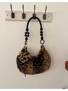 Borsa in peluche maculata appesa al muro, con manico di perline e ciondolo con nappina