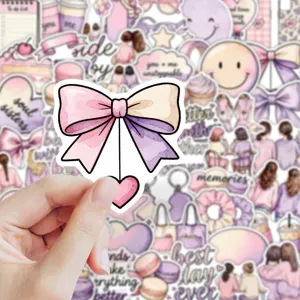Close-up of a watercolor pink and purple bow sticker with a dangling heart, held by hand