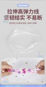Nahaufnahme einer transparenten elastischen Perlenschnur, während Hände rosa Perlen auffädeln
