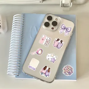 Pastel bow, flower and star stickers arranged on a clear phone case over a blue notebook