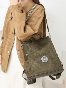 Olive green suede-look convertible women's backpack and handbag with a round metal accent, worn