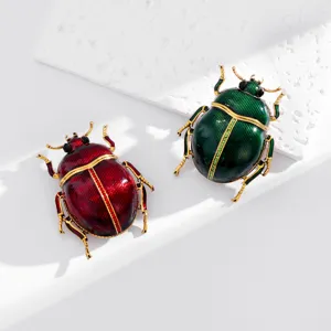 Close-up of red and green enamel beetle brooches with gold-tone frames and crystal accents