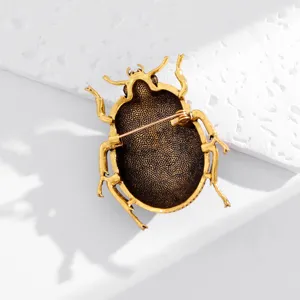 Close-up of the antique-gold beetle brooch back, showing its dark textured surface and pin clasp