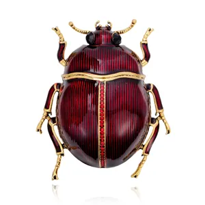Front view of a red enamel beetle brooch with gold-tone detailing and sparkling rhinestone accents