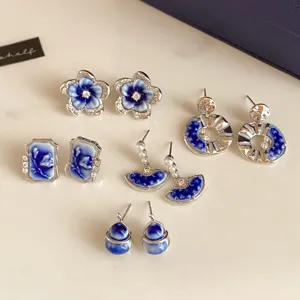 Flat lay of blue-and-white porcelain-style earrings in floral, square, fan, hoop and drop designs