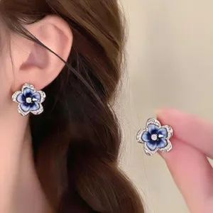 Close-up of blue-white enamel petals, a bright center and crystal-set silver edges, worn and held