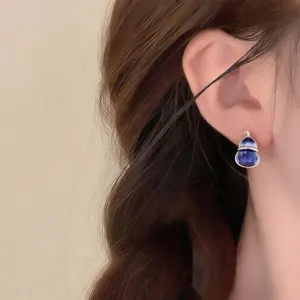 Side view of a model wearing a blue gourd-shaped earring with a silver-tone frame
