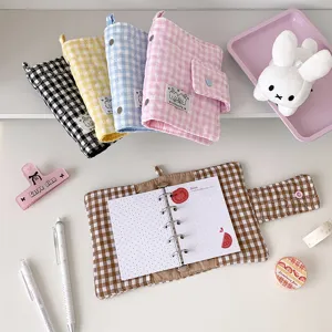 Fundas acolchadas de cuadros en varios colores, con broches de presión y un cuaderno marrón abierto