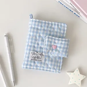 Detalle del tejido acolchado de cuadros azules y blancos, con cierre de corazón rosa y solapa