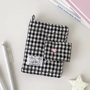 Vista cenital de una funda acolchada de cuadros blancos y negros, con cierre de corazón rosa y asa