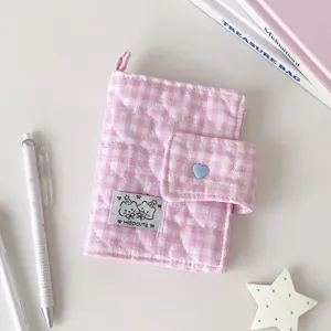 Vista plana de tela rosa a cuadros acolchada, con broche de corazón azul y etiqueta con osito