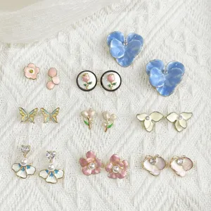 Colorful enamel flower, butterfly and tulip studs with pearl and crystal accents on white knit fabric