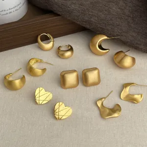 Flat lay of assorted matte gold-tone metal earrings in crescent, square, heart and abstract shapes