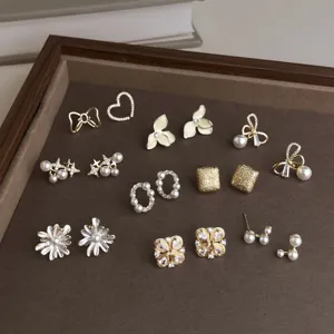 Gold-tone earrings with pearl and rhinestone accents arranged on a brown velvet display tray