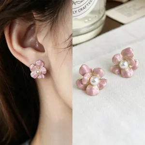Close-up of pink enamel flower studs with faux pearl centers and gold-tone rims, worn and displayed
