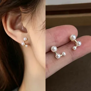 Close-up of curved gold-tone studs with three graduated faux pearls, shown worn and in hand