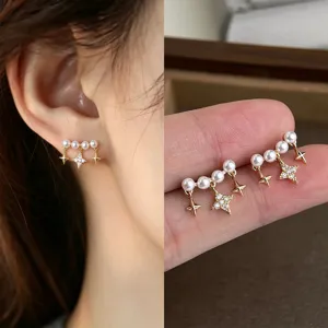 Gold star earrings with white faux pearls and a pavé star, shown worn and in a hand close-up