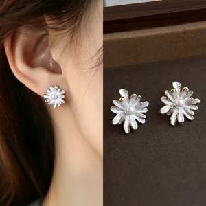 White enamel flower studs with pearl-like centers and gold-tone trim, shown worn and on velvet