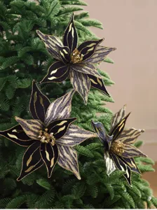 Trois fleurs de Noël en velours noir, rayées d’or et ornées de sequins, sur des branches de sapin