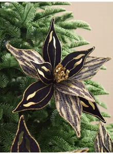 Gros plan sur une fleur de Noël noire et dorée, aux pétales pointus et au cœur scintillant