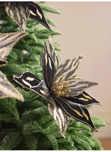 Pétales noirs effet velours, bordures dorées et cœur pailleté parmi les branches de sapin vert