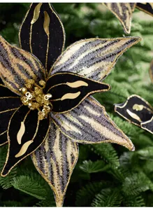Gros plan sur une fleur en velours noir, ornée de sequins dorés, de dentelle et d’un cœur décoré