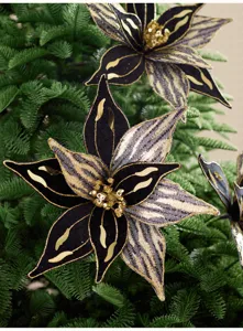 Gros plan de fleurs de Noël en velours noir et résille dorée, à cœur scintillant, sur un sapin