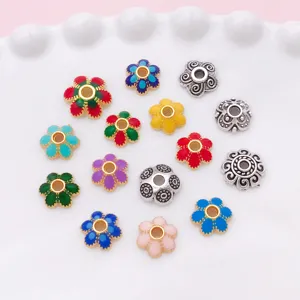 Vue de dessus de pièces florales émaillées colorées et argentées antiques sur une coupelle blanche