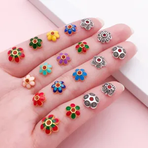 Perles émaillées colorées en forme de fleurs et entretoises argentées décorées sur une main