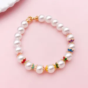 Détail d’un bracelet de fausses perles blanches, avec fleurs colorées dorées et fermoir doré