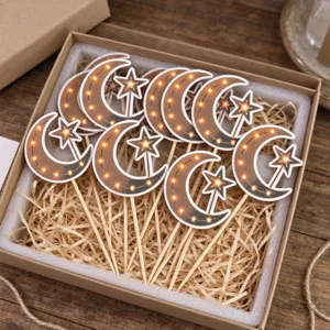 Close-up of crescent moon and star cake picks with gold dots, arranged in a kraft gift box
