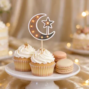 Moon-and-star topper with warm lights displayed above frosted cupcakes and macarons on a white stand