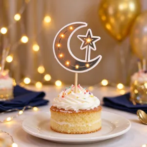 Close-up of a crescent moon and star cake topper glowing with warm lights above a frosted cupcake