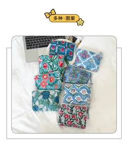 Vue à plat de petites pochettes en coton à fleurs colorées sur une literie blanche