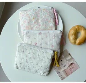 Trois pochettes fleuries à pompons sont posées sur une assiette blanche près d’un petit pain.