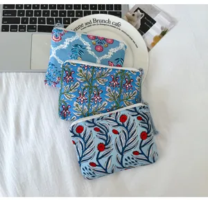 Trois pochettes zippées bleues superposées, avec des motifs de feuilles et fleurs rouges sur tissu