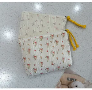 Deux pochettes en tissu crème superposées, à motifs floraux et rayés, avec tirettes jaunes en corde