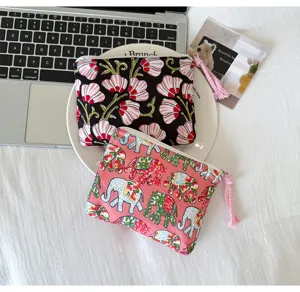 Deux pochettes à motifs : fleurs roses sur fond noir et éléphants sur fond rose avec pompon.