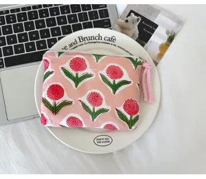 Détail d'une pochette en tissu rose à fleurs rouges, avec fermeture éclair et tirette nouée