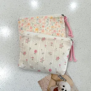 Deux petites pochettes en coton fleuri, à rayures texturées, avec zip et cordons roses