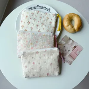 Trois pochettes fleuries en coton, zippées, avec des pompons colorés, présentées à plat