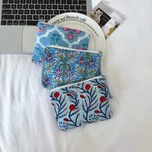 Trois porte-monnaie bleus en coton imprimé floral, avec fermeture zippée et tirettes à pompon