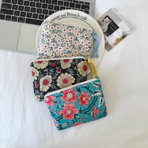Trois pochettes fleuries en coton à fermeture zippée, crème, noire et turquoise, vues de dessus