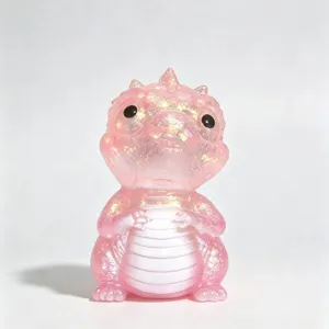 Pink glittery dragon figurine with a pearlescent finish, seated against a clean white background