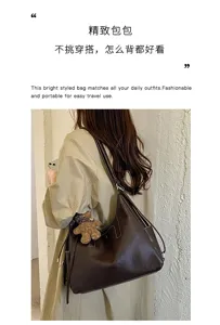 Brown faux-leather shoulder bag worn over a light coat, showing its spacious shape and long straps