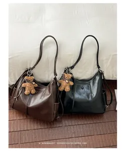 Brown and black faux-leather bags with shoulder straps and teddy bear charms, displayed side by side