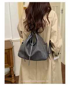 Gray leather-look convertible tote backpack with drawstring and metal clasp, worn on the back