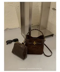 Detail of brown suede bag with braided handle, gold clasp, shoulder strap and matching zip pouch